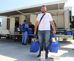 College student with groceries in front of Mobile Food Pantry