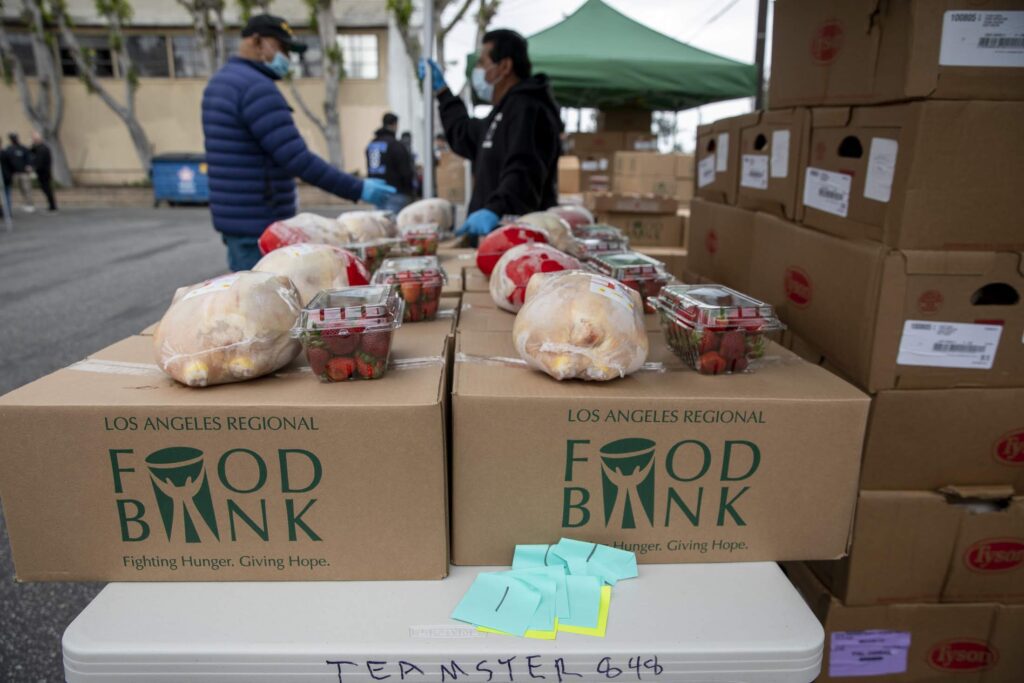 Boxes of shelf-stable food products, frozen chicken and fresh strawberries are lined up in preparation for a drive through distribution for those in need at an event hosted by the Los Angeles Regional Food Bank.