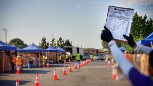 A LA Regional Food Bank volunteer holds up a COVID-19 intake form at a drive-through food distribution.