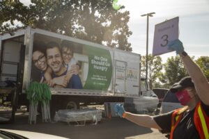 A LA Regional Food Bank volunteer directs cars at a drive-through food distribution.