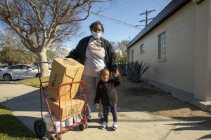 Mrs. Carson and her 2-year-old granddaughter take a picture next to food kits they received at a drive-through food distribution.
