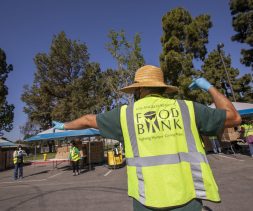 A back view of a LA Regional Food Bank employee directing traffic at a drive-through food distribution in South Gate, CA.
