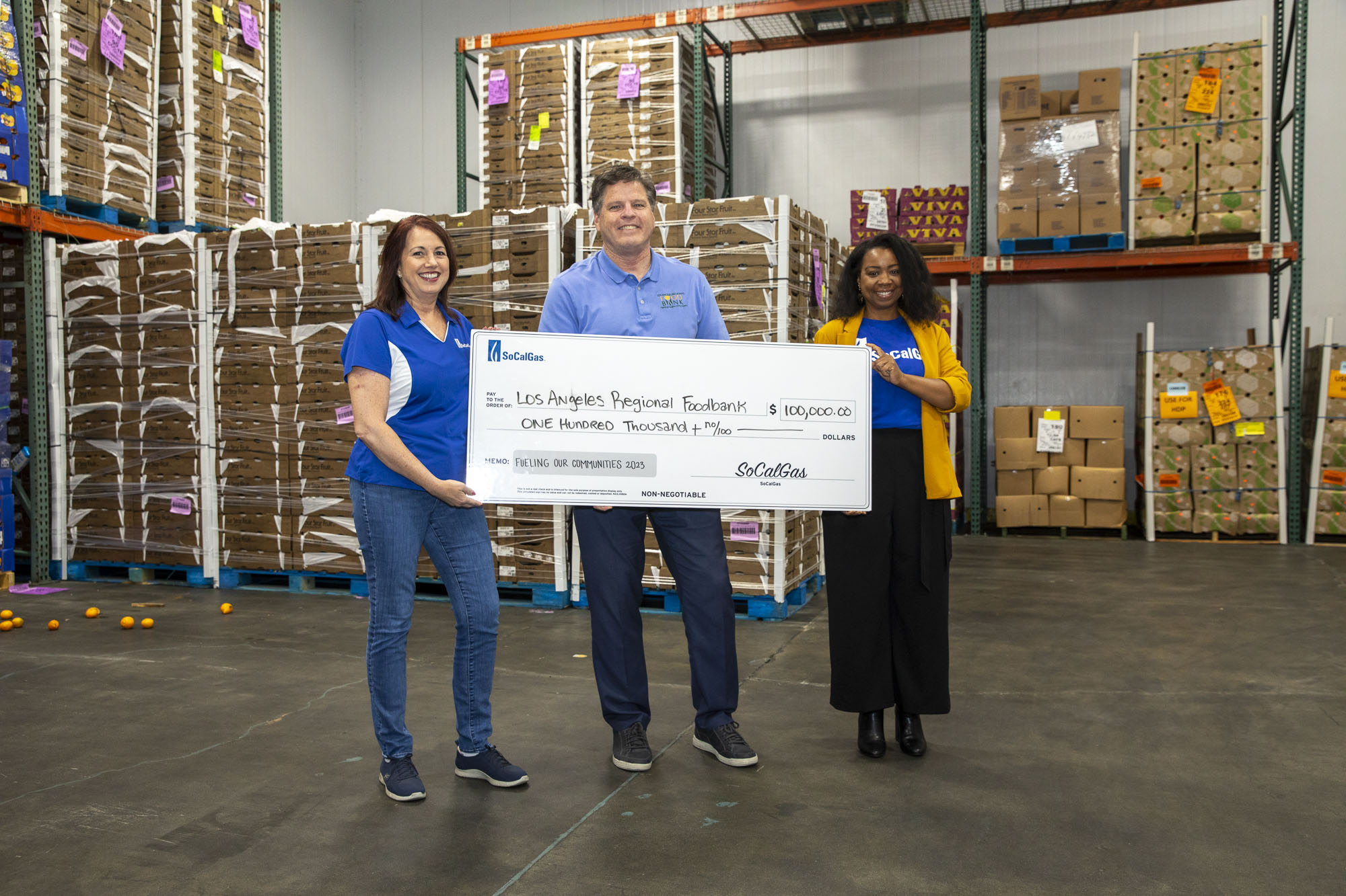 Michael Flood holding a check with two SoCal Gas employees