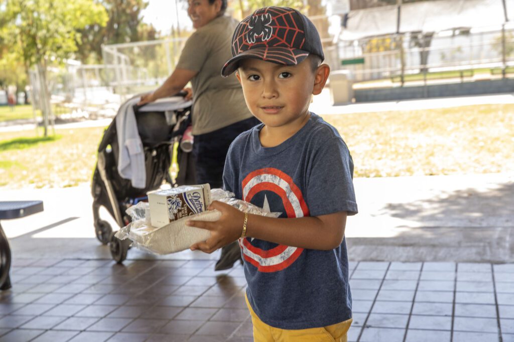 A small boy holds his lunch during a free summer meals distribution at Bristow Park during the 2023 summer