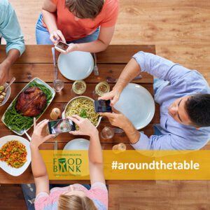 Overview shot of three people aiming over their food around a dinner table before eating/