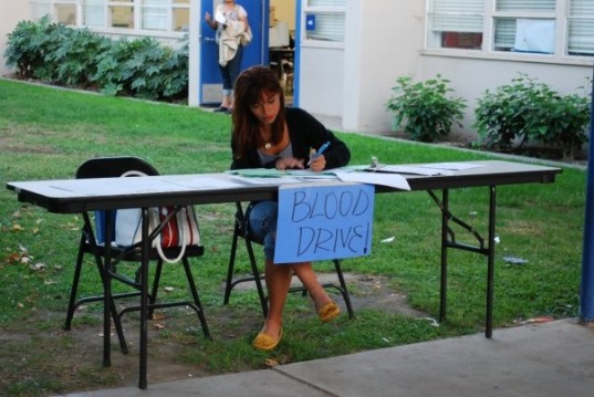 In high school, promoting sign ups for  semesterly blood drive! A high school student at a table promoting sign up for a blood drive.