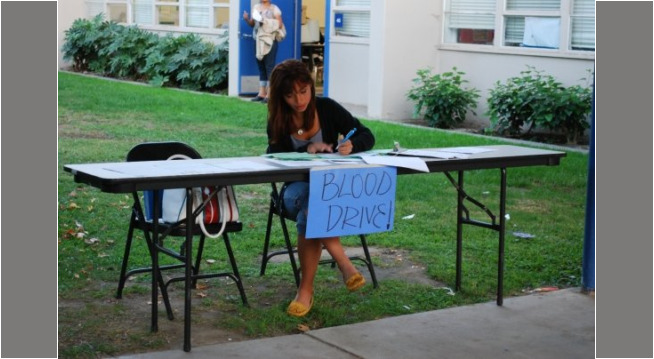 In high school, promoting sign ups for semesterly blood drive! A high school student at a table promoting sign up for a blood drive.