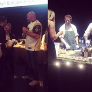 A dimly lit event buzzes with interaction. On the left, a few individuals are engaged in conversation. On the right, chefs from the Los Angeles Regional Food Bank in aprons prepare food behind a counter adorned with a variety of fresh ingredients.